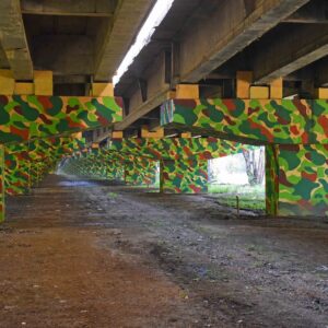 A motorway underpass painted in yellow and green camouflage