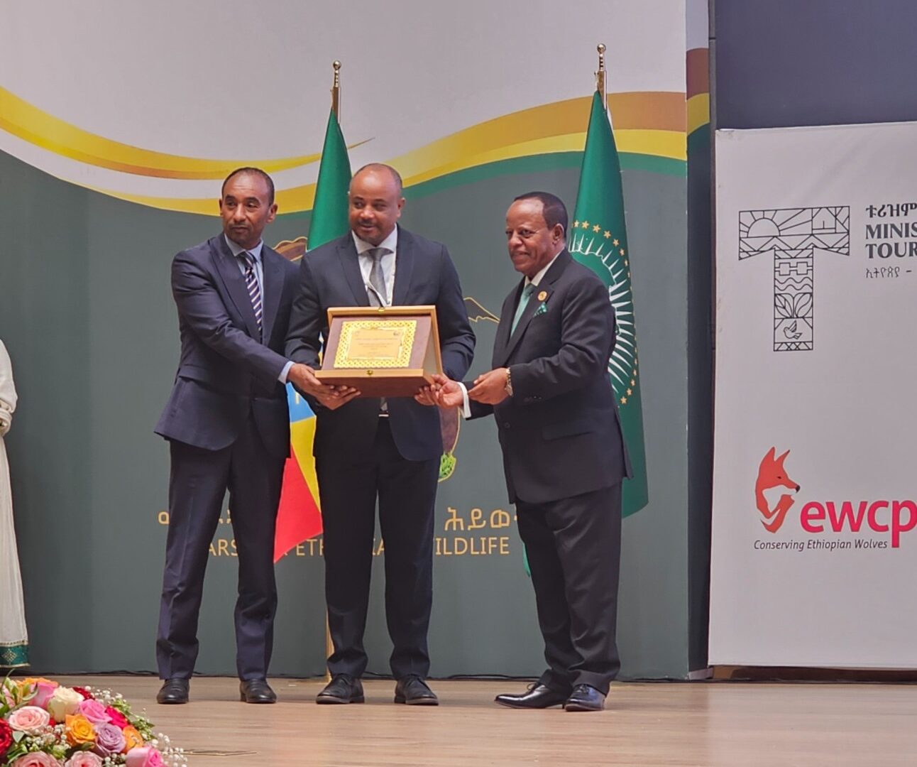 Three people on stage at an awards ceremony