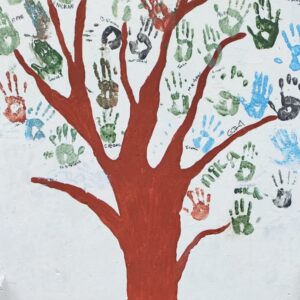 A painted tree with childrens handprints creating the leaves