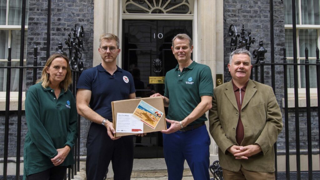 A group of people handing in a large postcard to 10 Downing Street