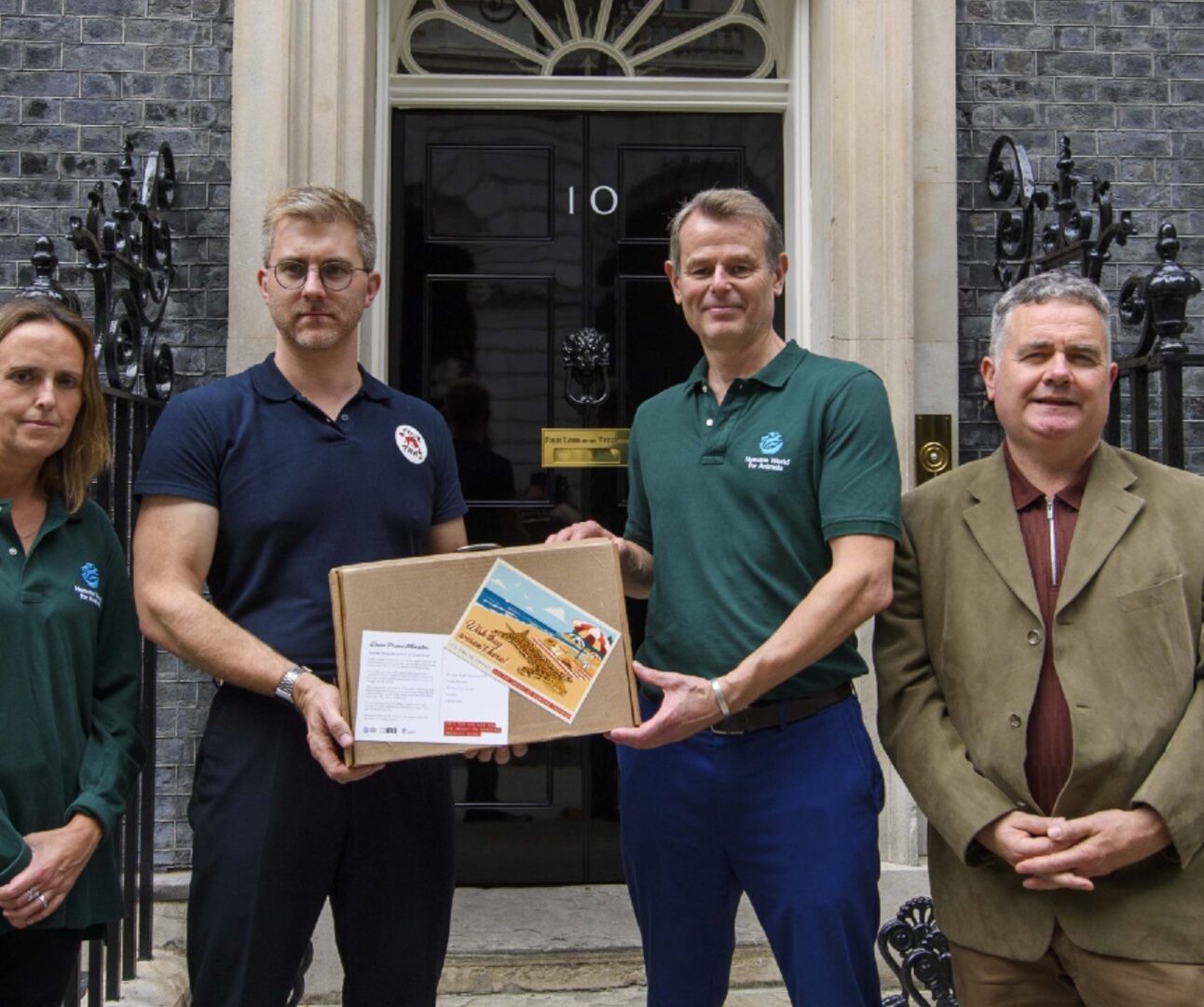 A group of people handing in a large postcard to 10 Downing Street
