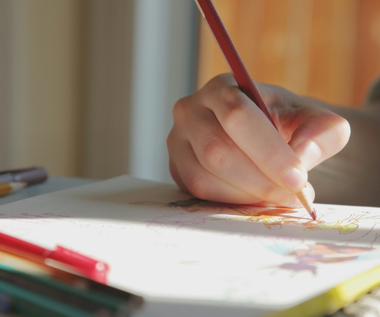 A close-up image of a young person's hand colouring in with pencils