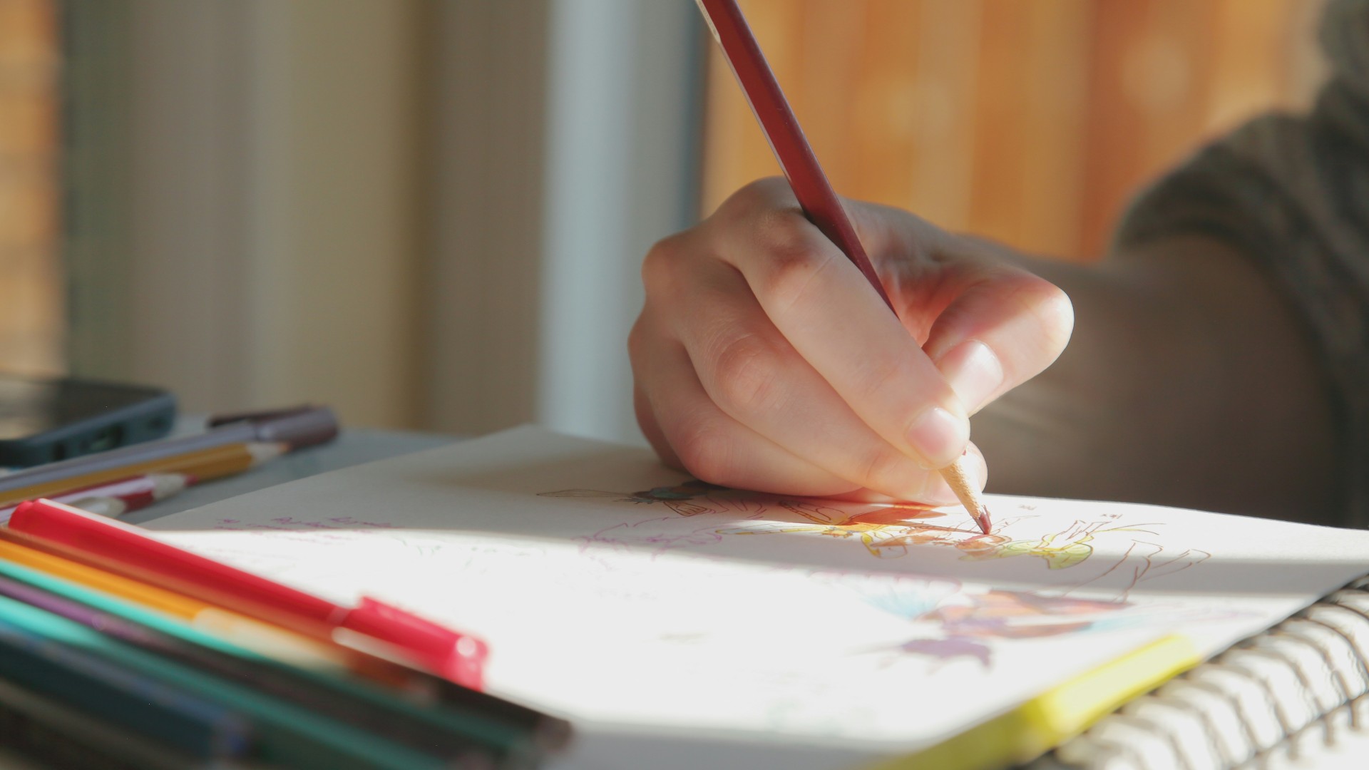 A close-up image of a young person's hand colouring in with pencils